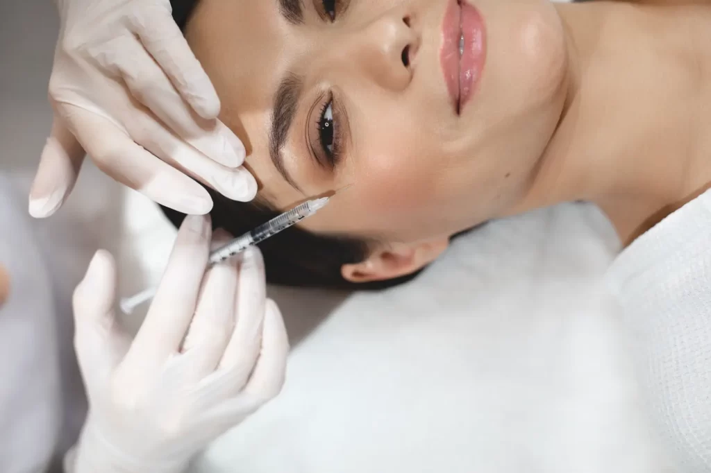 Provider administering a facial injection near the under-eye area during a cosmetic treatment
