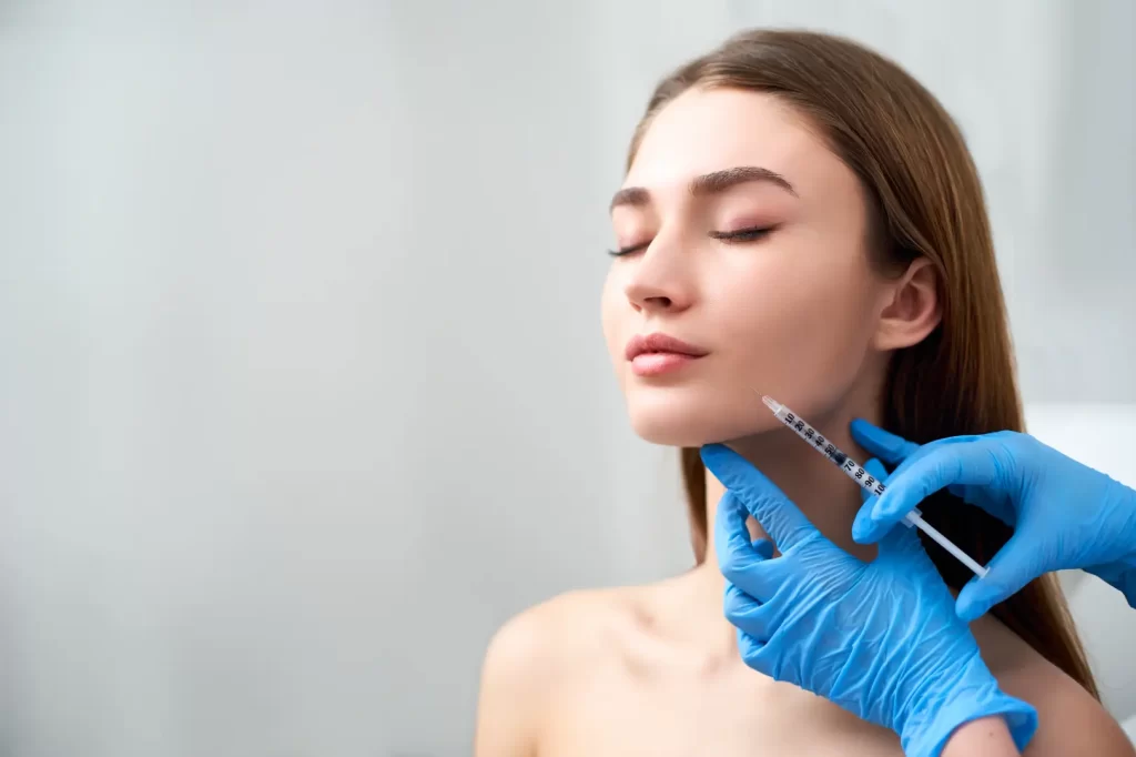 Provider preparing a facial injection near a woman’s jawline during a cosmetic treatment