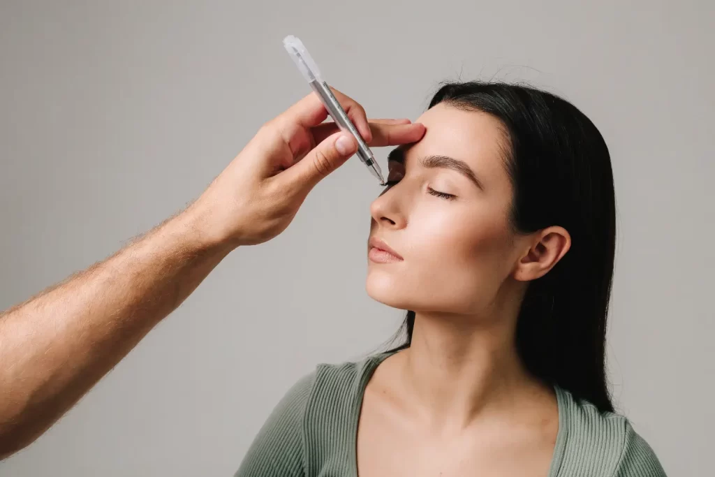 Provider preparing a cosmetic injection near a woman’s forehead during a facial treatment