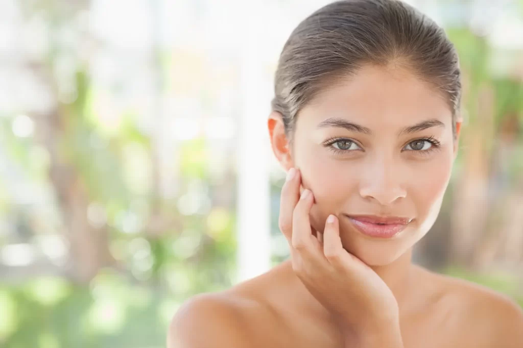 Woman with smooth glowing skin resting her hand on her cheek
