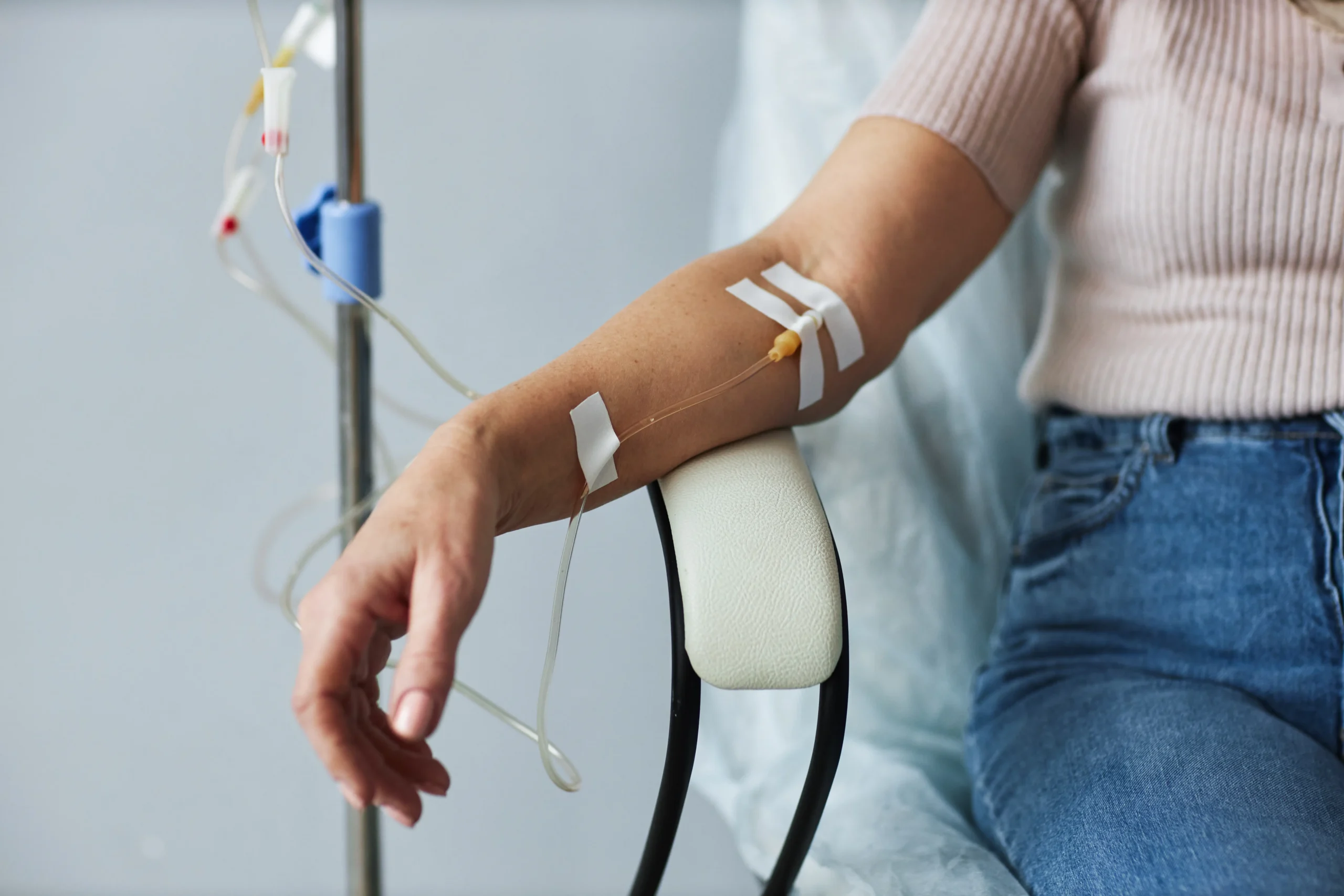 Person seated with an IV line attached to their arm during a treatment session